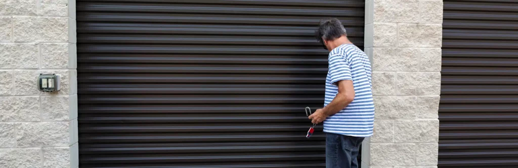 Man in striped shirt unlocking a self storage unit.